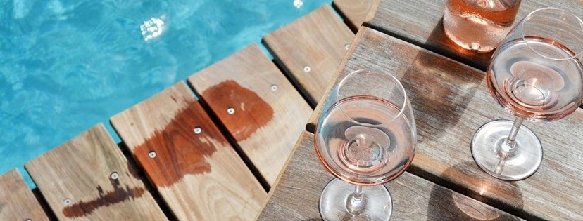 verre de rosé au bord d'une piscine avec trace de pied mouillé