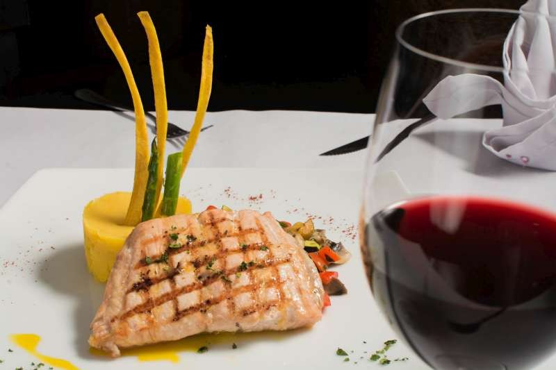 Assiette avec du poisson grillé avec un verre de vin rouge