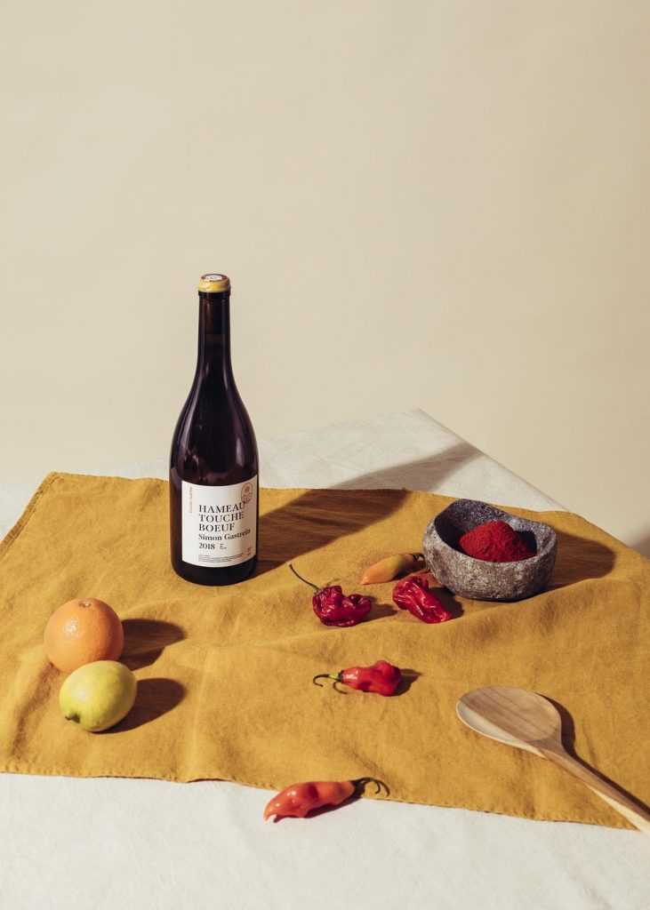 bouteille de vin sur une serviette avec agrumes, piment et cuillère en bois