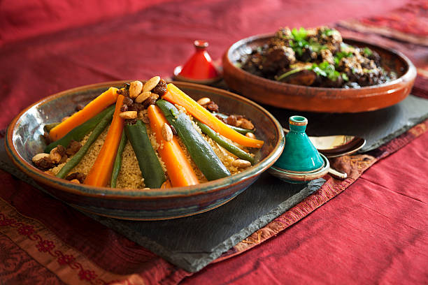 Couscous avec légumes et viande, dans des tajines sur une nappe en lin.